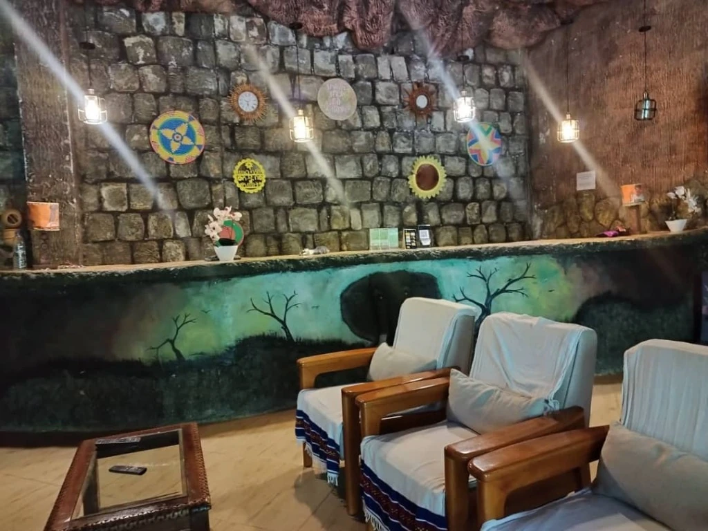 Lodge reception lounge with rustic stone wall, woven Ethiopian baskets and armchairs